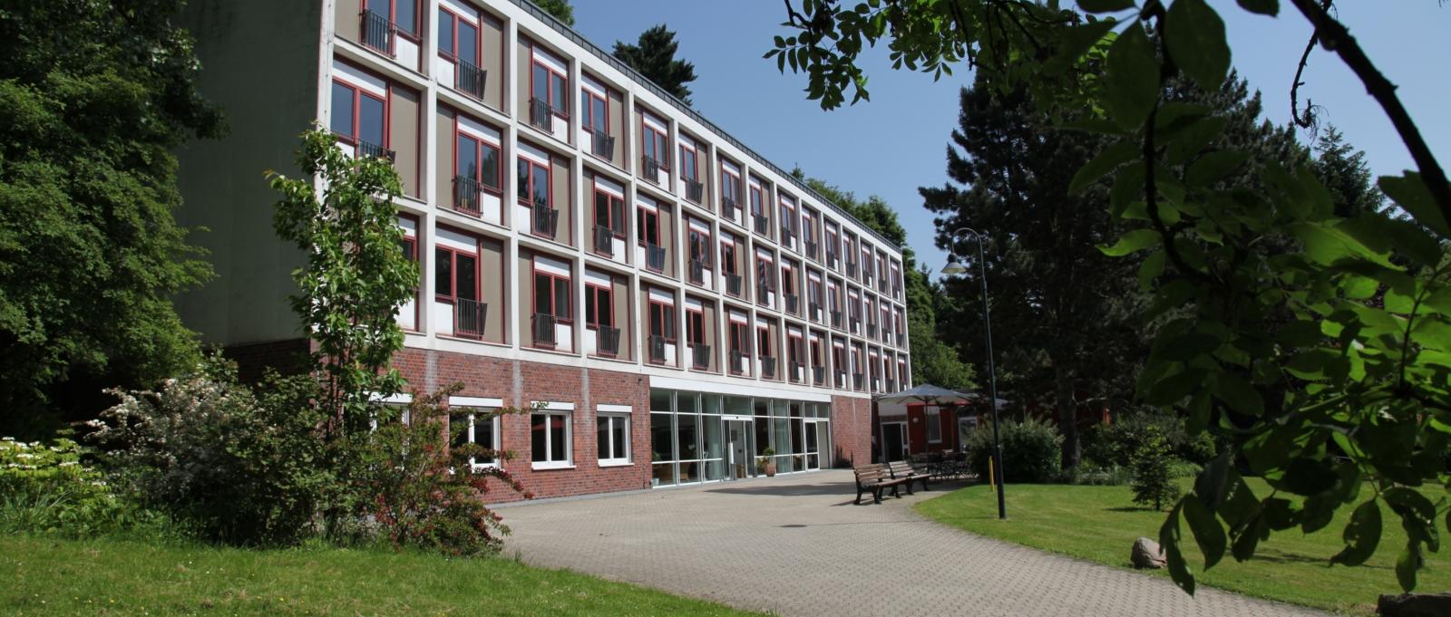Ansicht von derlinken Seite aus auf das Haus Marienhof. Äste fallen am oberen rechten Bildschirmrand in das Bild herein.