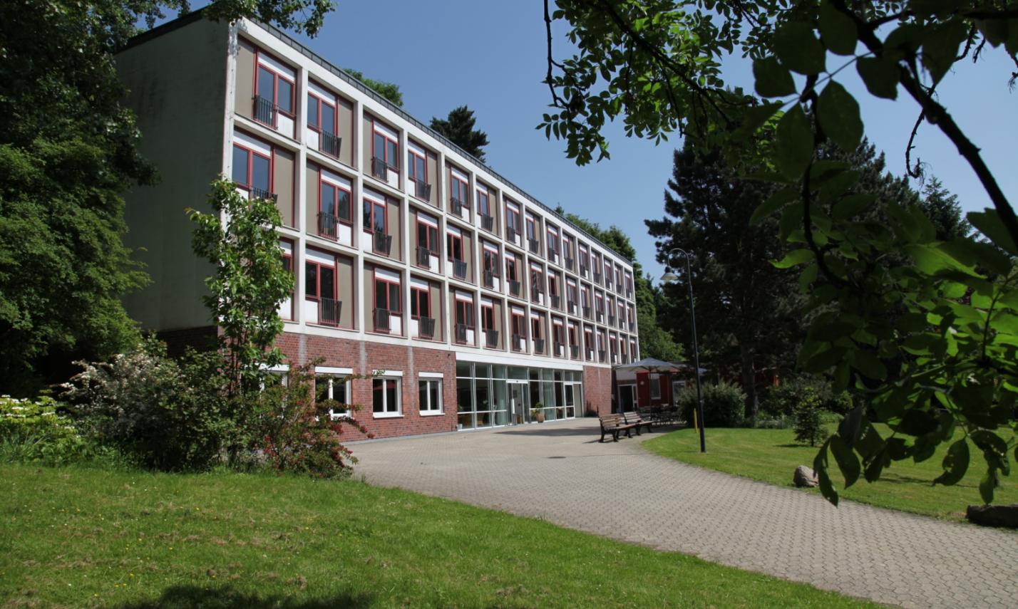 Ansicht von derlinken Seite aus auf das Haus Marienhof. Äste fallen am oberen rechten Bildschirmrand in das Bild herein.