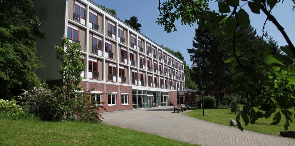 Ansicht von derlinken Seite aus auf das Haus Marienhof. Äste fallen am oberen rechten Bildschirmrand in das Bild herein.